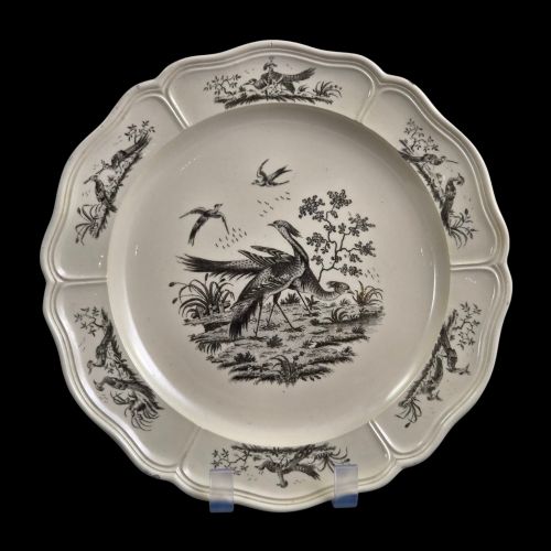 fig 2. A pair of round cream-coloured earthenware plates featuring monochrome transfer prints of birds and moulded scalloped rims.