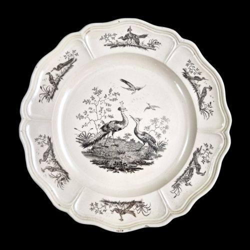 fig 5. A pair of round cream-coloured earthenware plates featuring monochrome transfer prints of birds and moulded scalloped rims.
