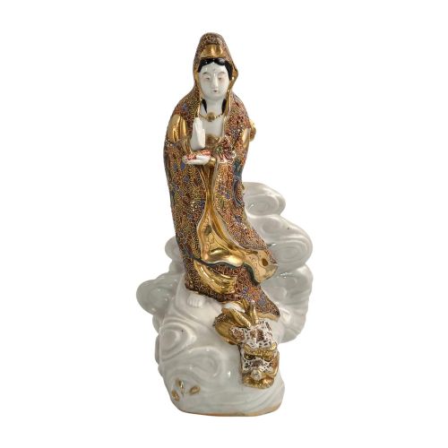 fig 1. A Japanese Kutani porcelain figure of the deity Kannon in detailed patterned robes, standing atop a white sea dragon amidst sculpted waves.