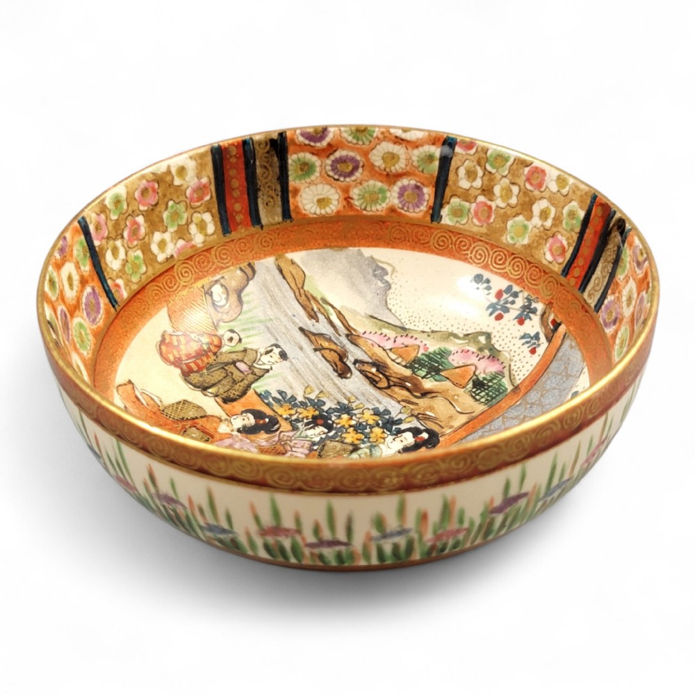 A round Japanese Kyoto Satsuma earthenware bowl featuring hand-painted figures, floral borders, and gold gilding over a cream crackle glaze.