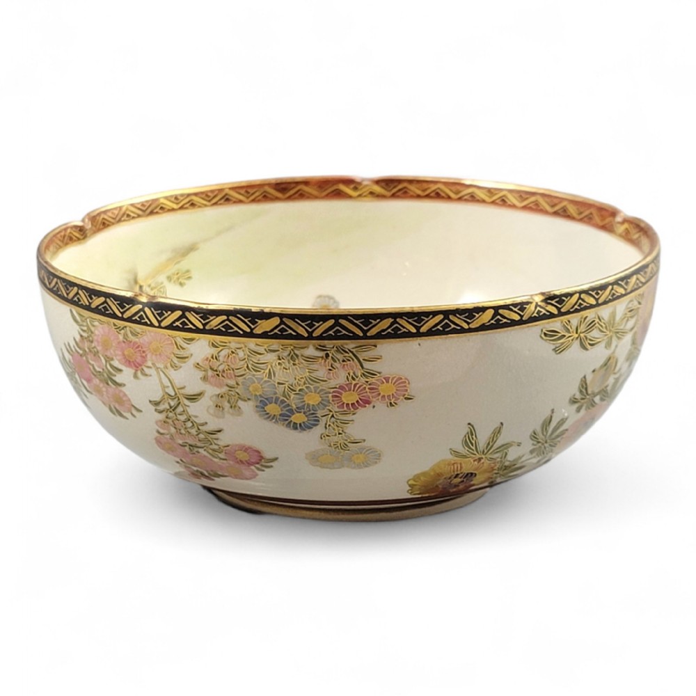 A cream-coloured Meiji period Satsuma earthenware bowl hand-painted with floral motifs and finished with a gilded border.