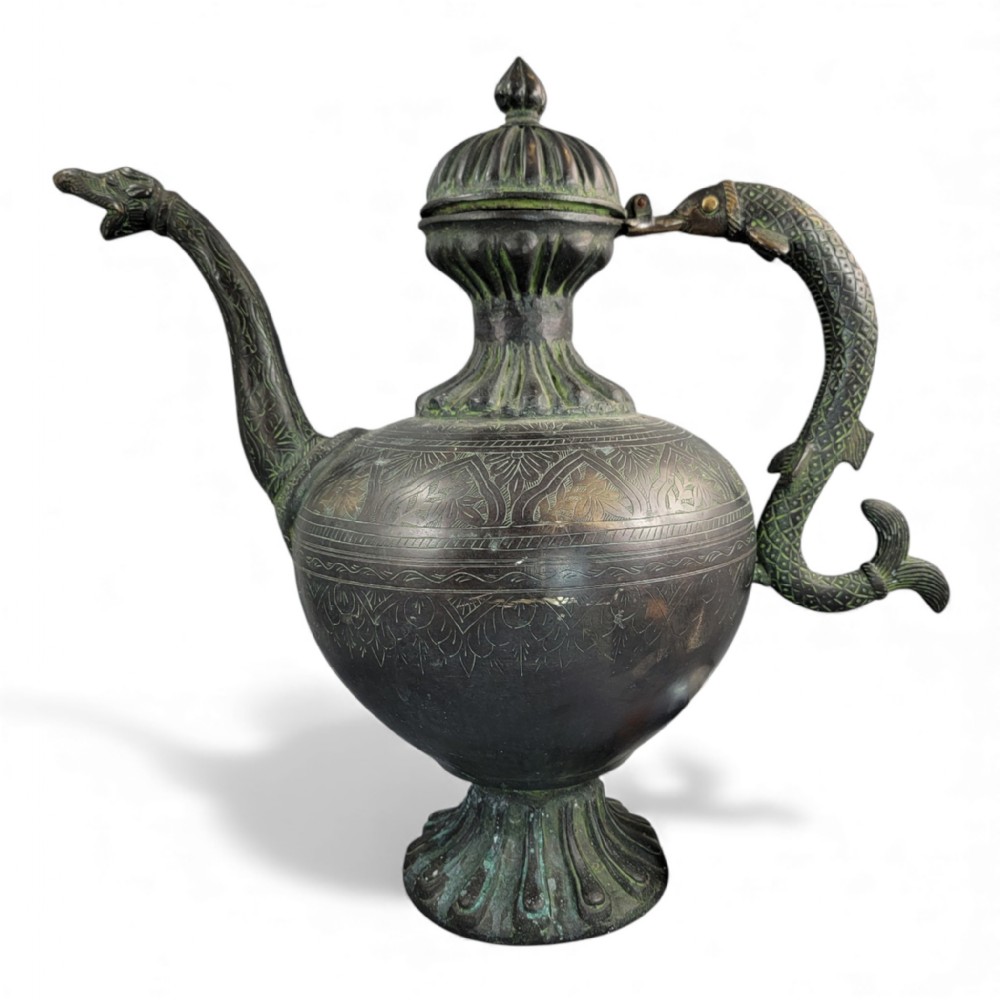 An antique dark bronze Indian aftaba ewer featuring an engraved bulbous body, a creature-shaped spout, a fluted base, and a Makara handle.