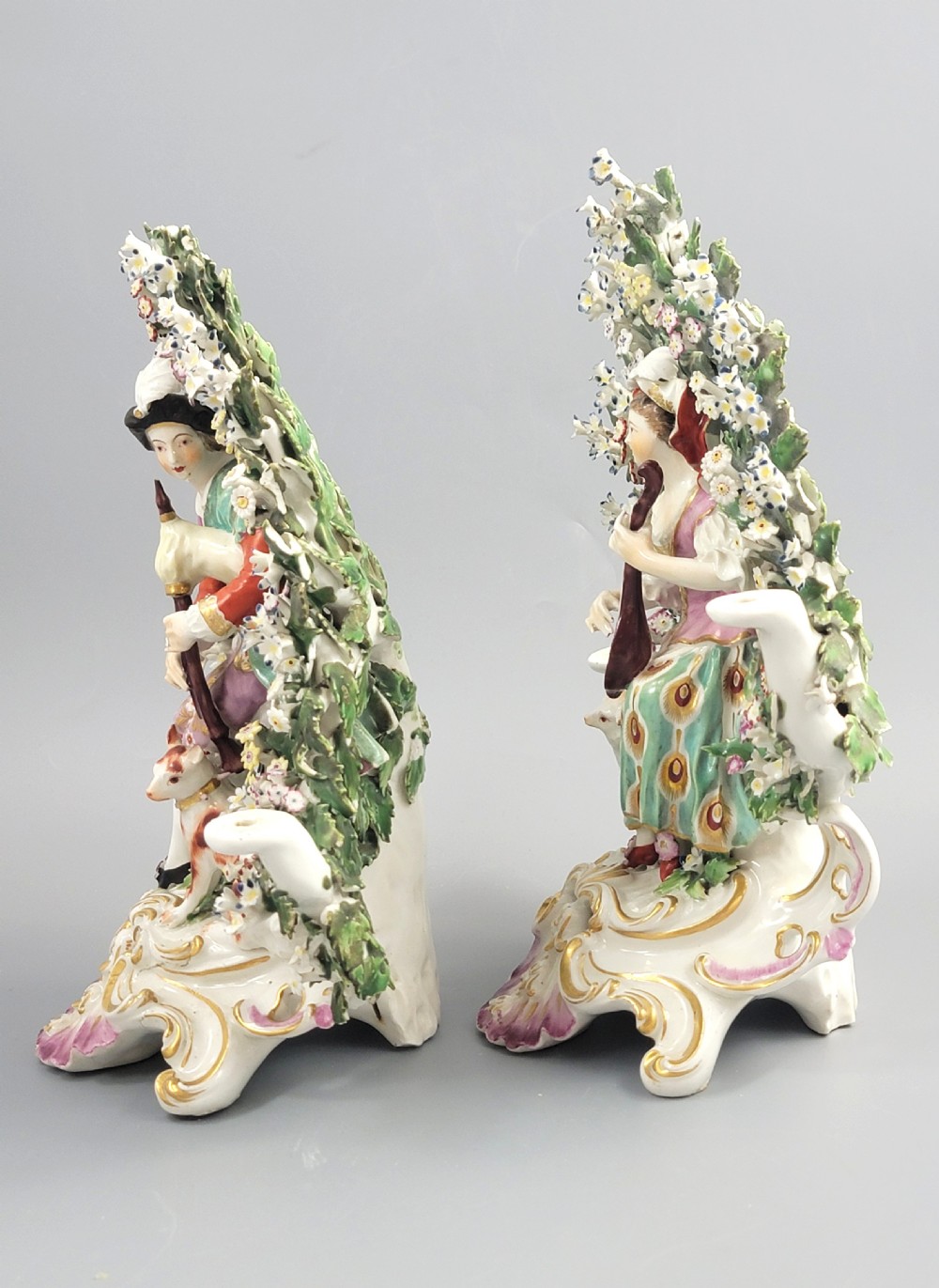 A pair of 18th-century English Derby porcelain candlestick figures depicting musicians surrounded by intricate floral bocage on Rococo scroll bases. View II