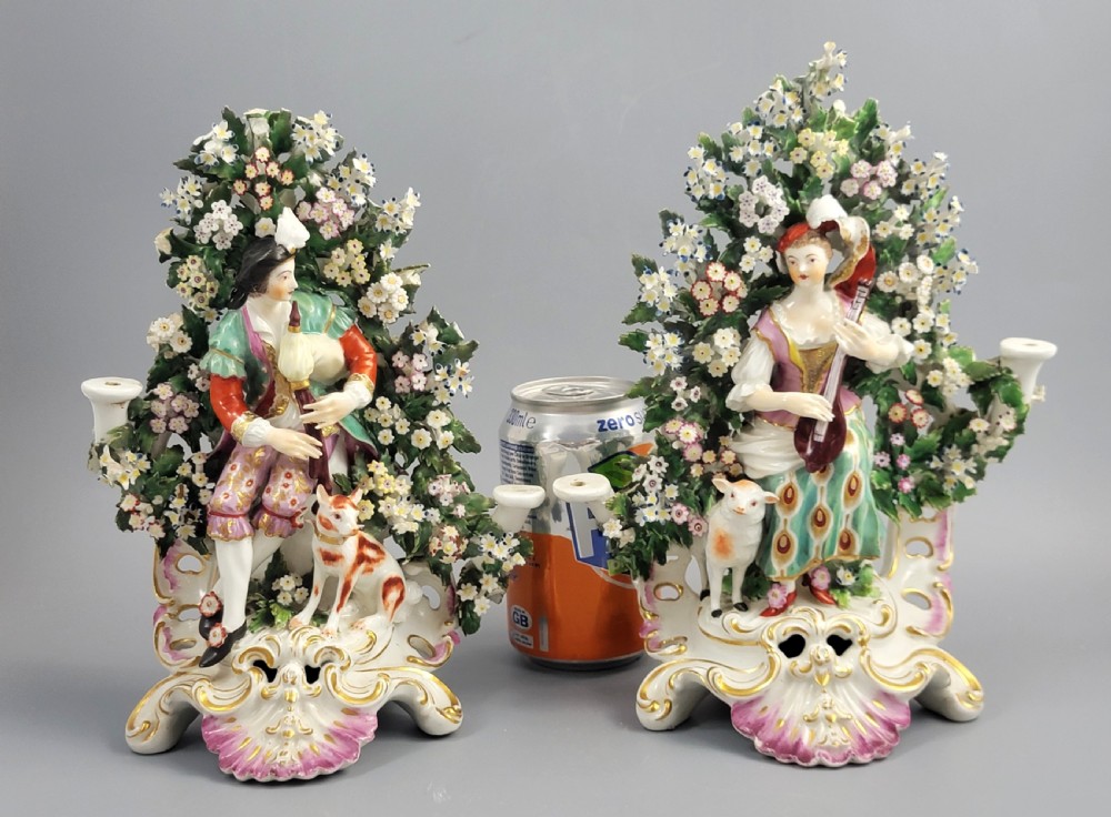 A pair of 18th-century English Derby porcelain candlestick figures depicting musicians surrounded by intricate floral bocage on Rococo scroll bases. View V
