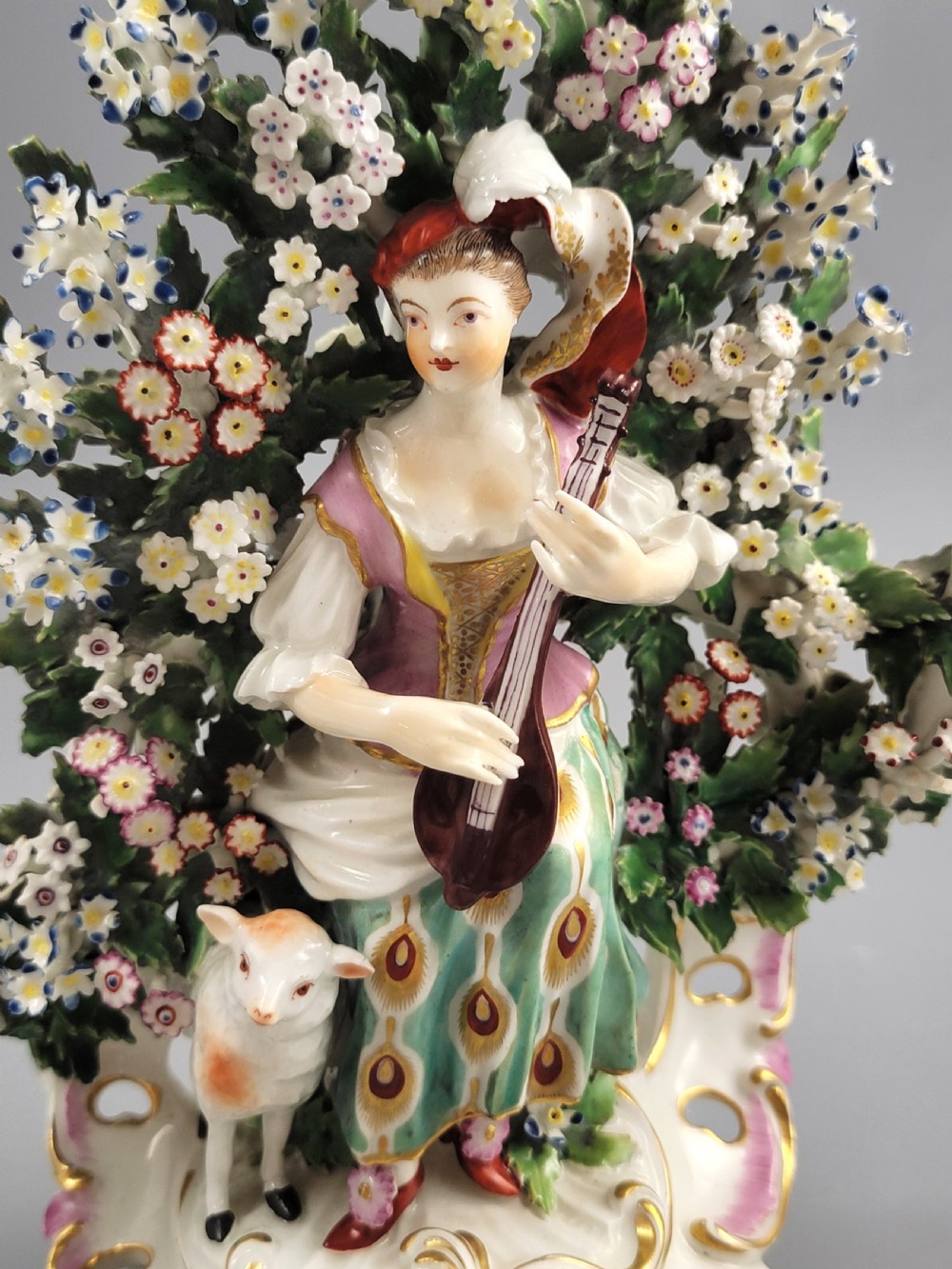 A pair of 18th-century English Derby porcelain candlestick figures depicting musicians surrounded by intricate floral bocage on Rococo scroll bases. View IX