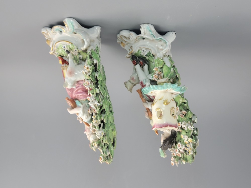 A pair of 18th-century soft-paste Derby porcelain candlesticks depicting a male and female musician seated before leafy floral bocage backdrops. View V