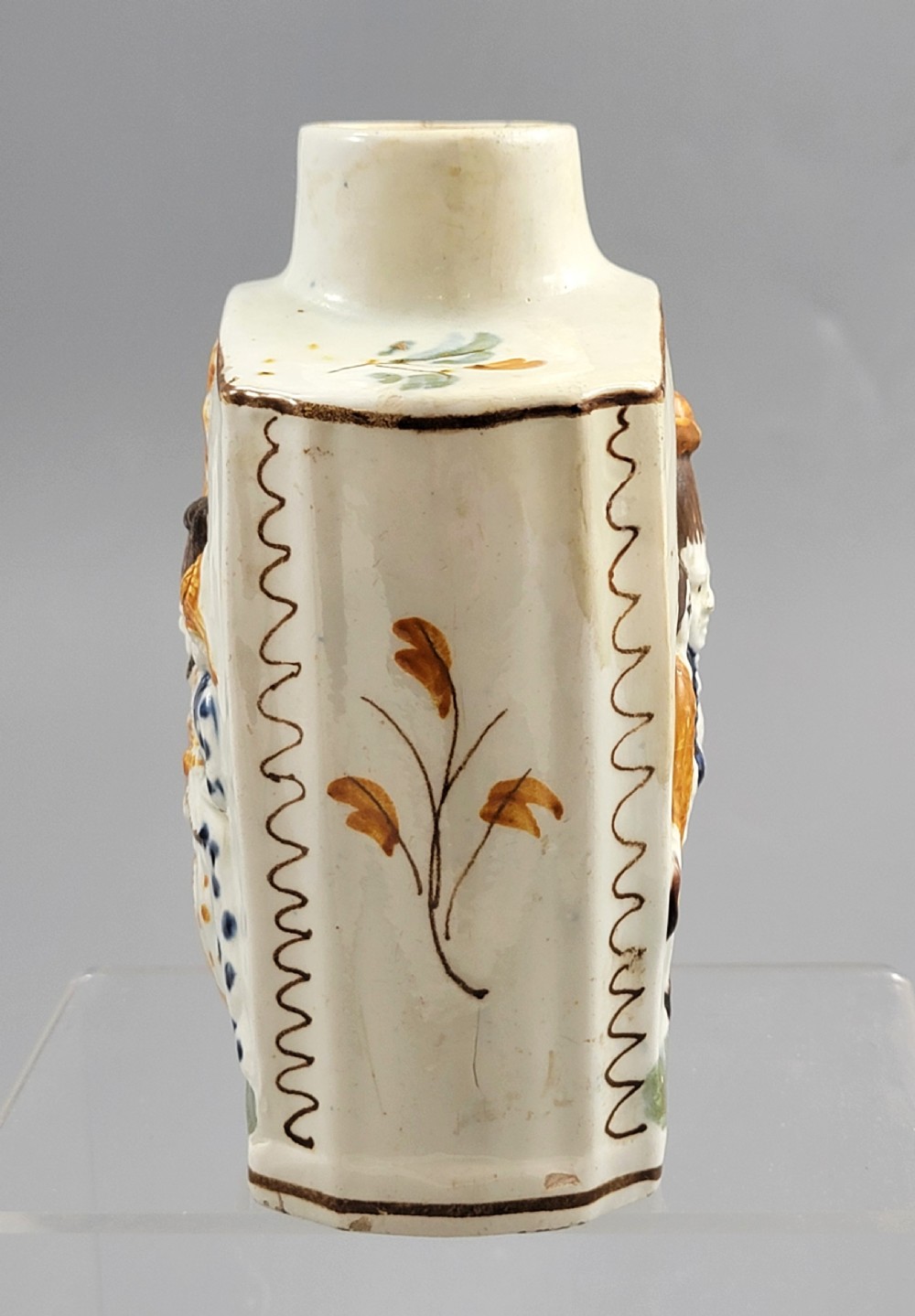 A late 18th-century cream-coloured pearlware tea caddy featuring moulded relief figures painted in ochre and cobalt blue glazes. View III