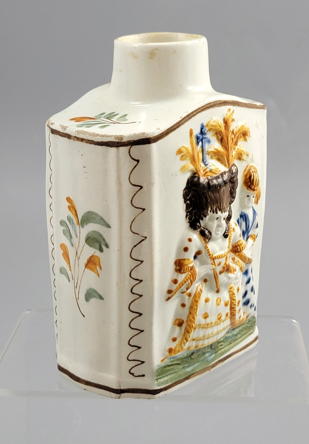 A late 18th-century cream-coloured pearlware tea caddy featuring moulded relief figures painted in ochre and cobalt blue glazes. View VIII