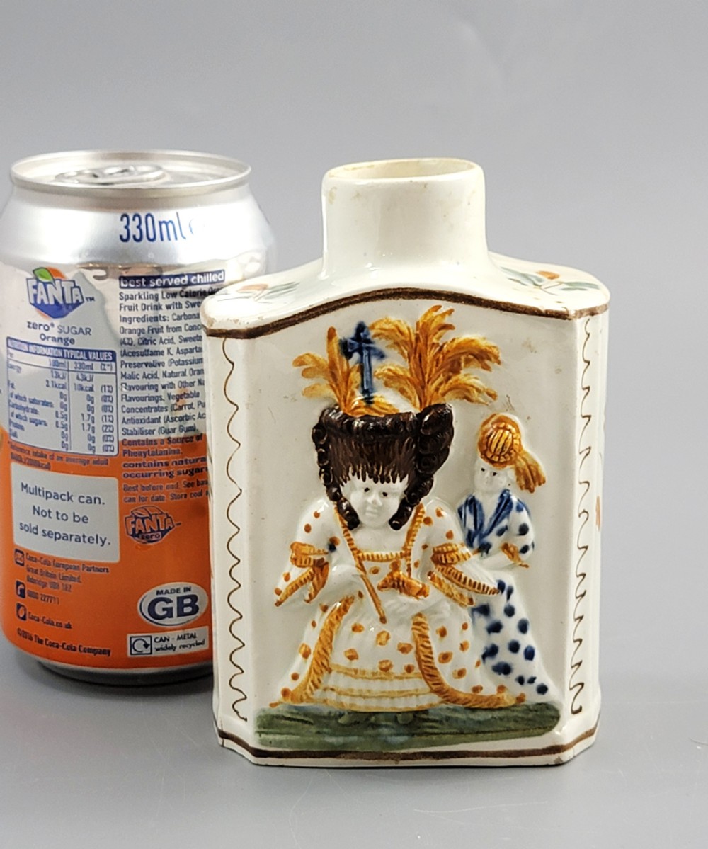 A late 18th-century cream-coloured pearlware tea caddy featuring moulded relief figures painted in ochre and cobalt blue glazes. View XI