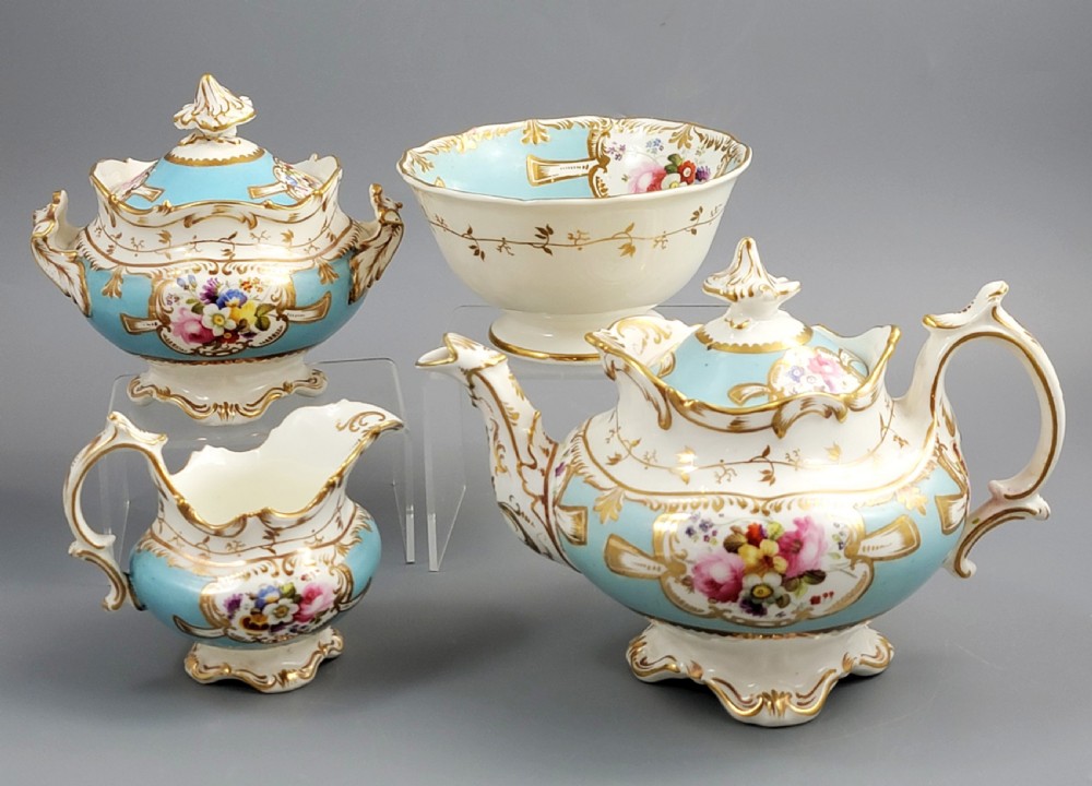 A four-piece antique French porcelain tea service featuring turquoise and white ground, hand-painted floral reserves, and ornate scrolled gold handles.