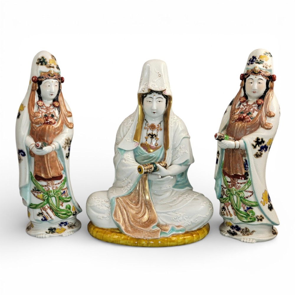 A set of three late nineteenth-century Japanese Kutani porcelain figures depicting Kannon flanked by two standing attendants, finished in white glaze with gilded and polychrome enamelled robes.