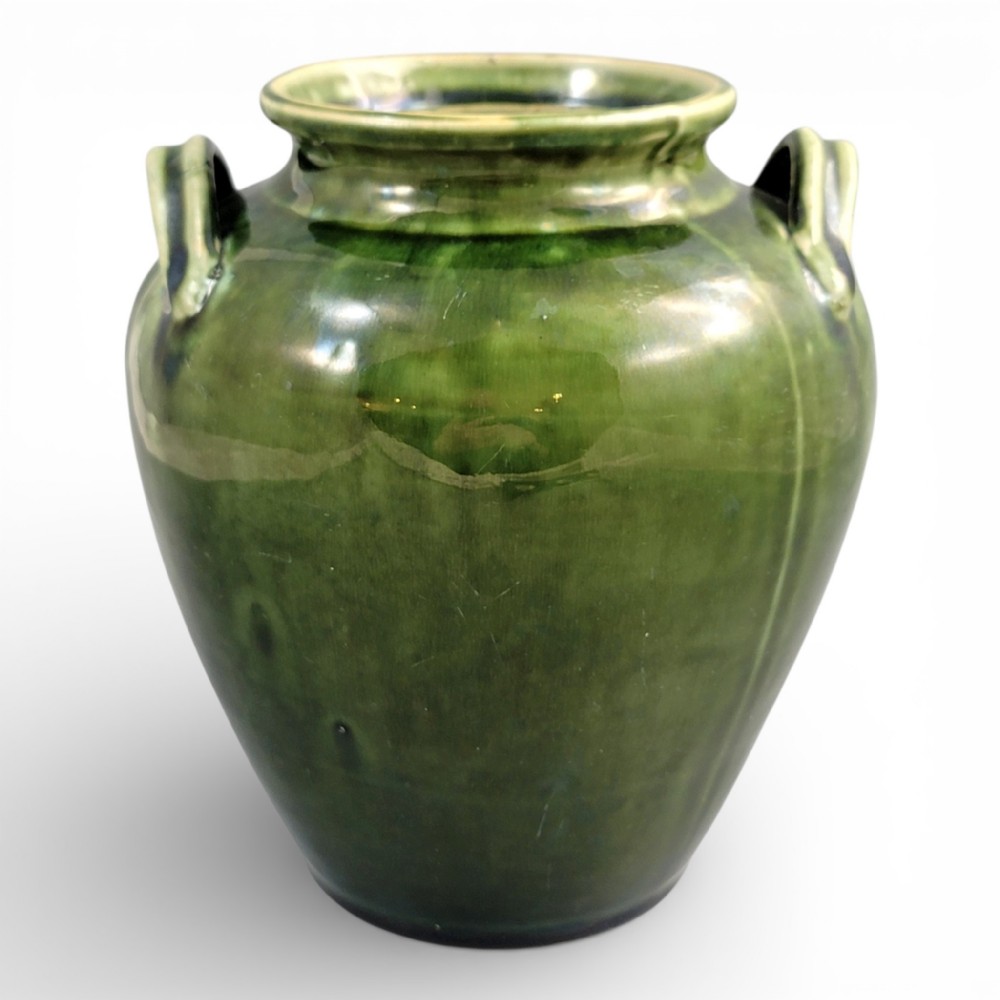 A 19th-century French green glazed terracotta confit jar featuring two handles near the flared rim.