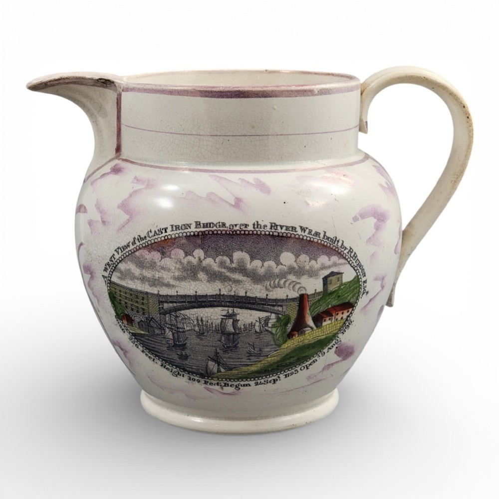 An antique pearlware jug featuring pink splash lustre glaze details and a transfer-printed central panel depicting the River Wear cast iron bridge.
