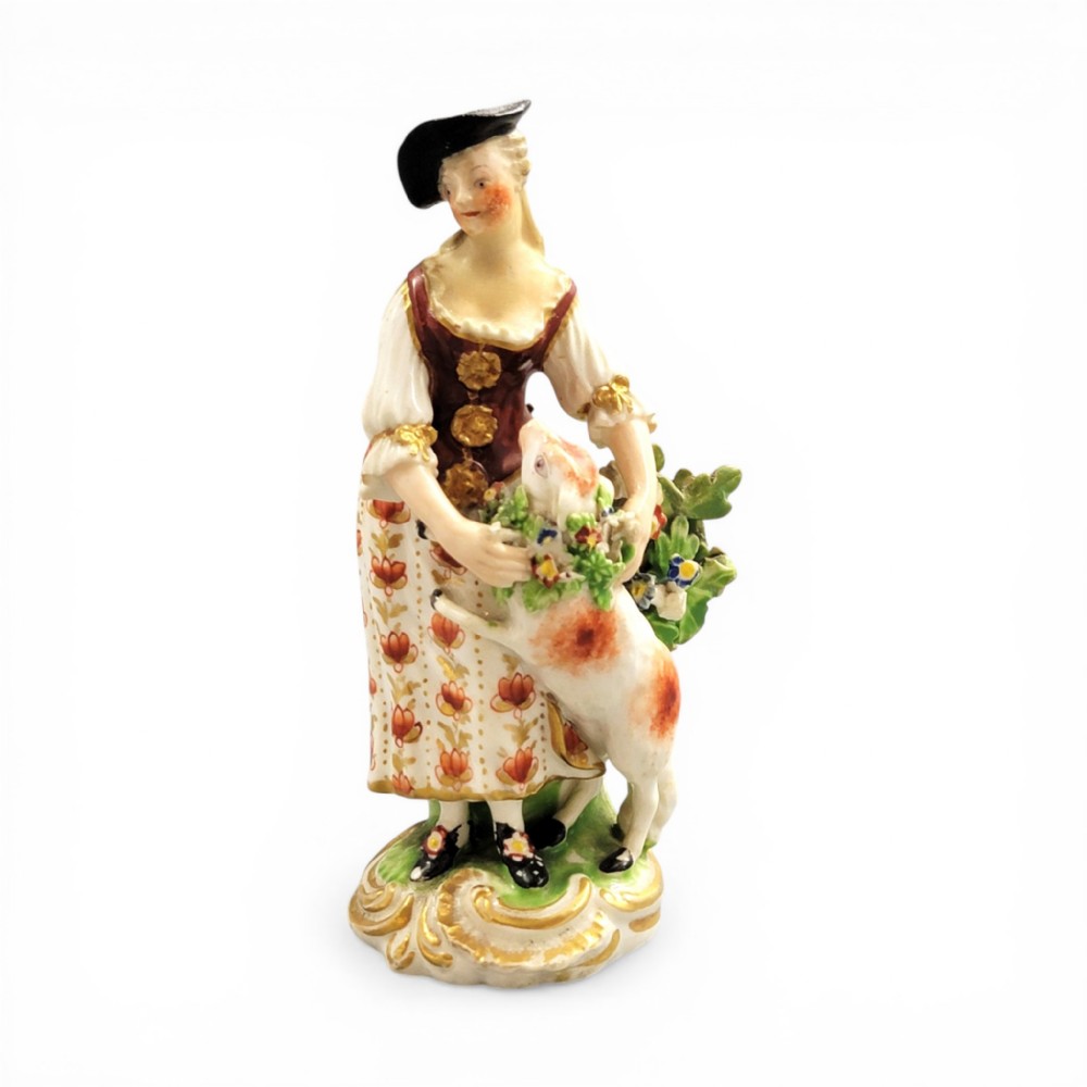 An 18th-century Derby soft-paste porcelain figurine depicting a shepherdess with a lamb on a gilded Rococo scroll base.