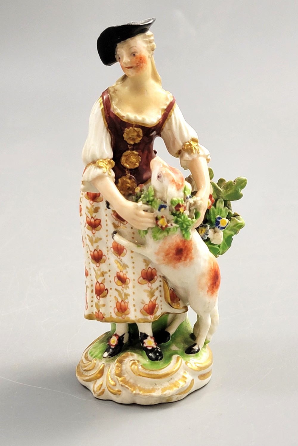 An 18th-century Derby soft-paste porcelain figurine depicting a shepherdess with a lamb on a gilded Rococo scroll base. View II
