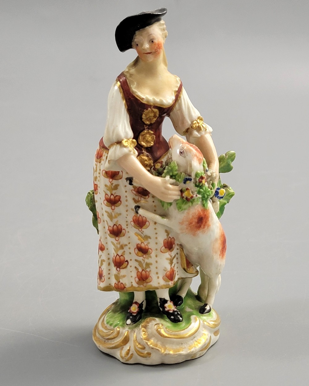 An 18th-century Derby soft-paste porcelain figurine depicting a shepherdess with a lamb on a gilded Rococo scroll base. View VI