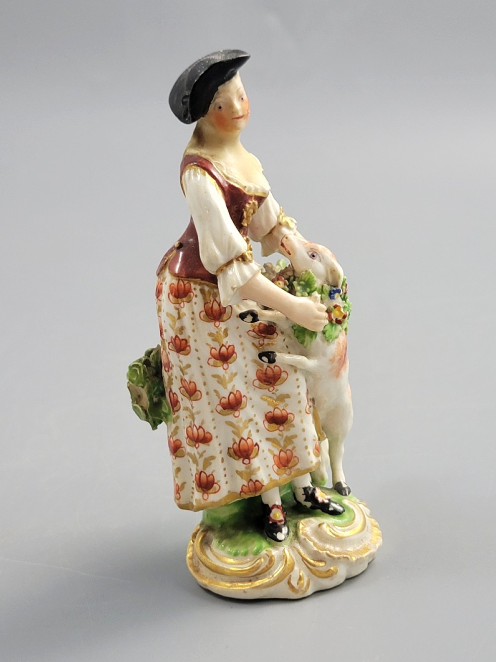 An 18th-century Derby soft-paste porcelain figurine depicting a shepherdess with a lamb on a gilded Rococo scroll base. View VII