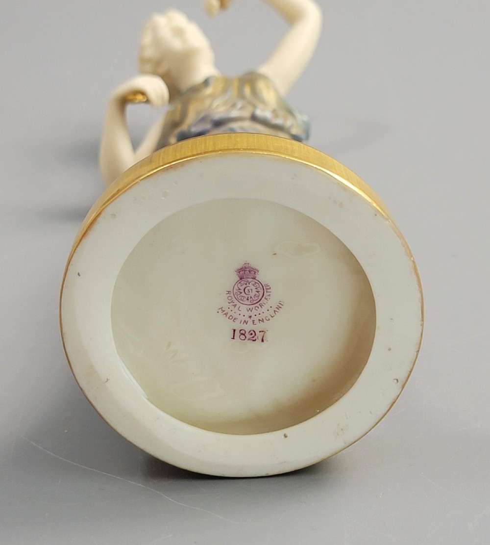 A porcelain figurine of a woman wearing classical draped robes with gilded trim standing on a circular base. View VI