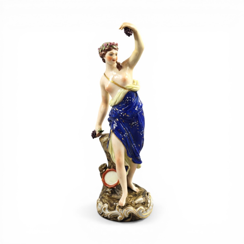 A nineteenth-century Samson Paris porcelain figure of a Bacchante wearing a patterned cobalt blue drape and holding grapes on a scrollwork base.