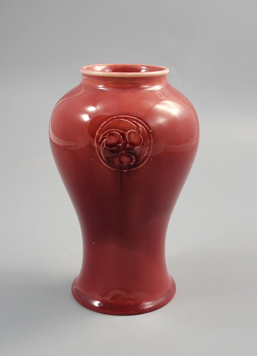 A red glazed earthenware vase featuring a baluster shape with an embossed roundel medallion near the rim. View II