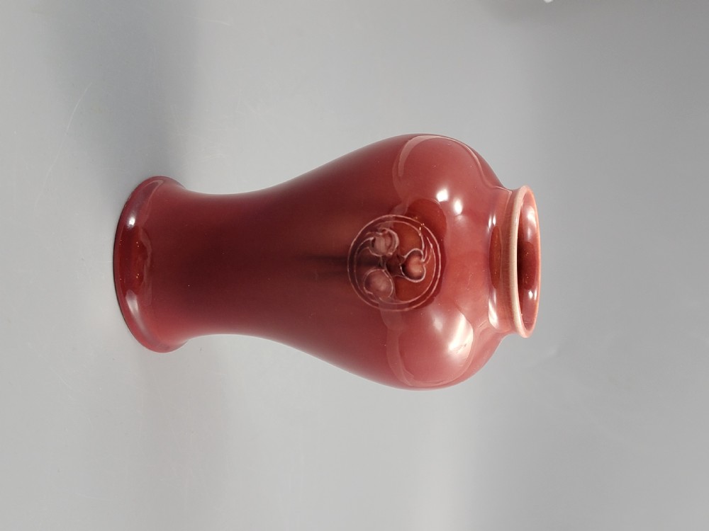 A red glazed earthenware vase featuring a baluster shape with an embossed roundel medallion near the rim. View IV
