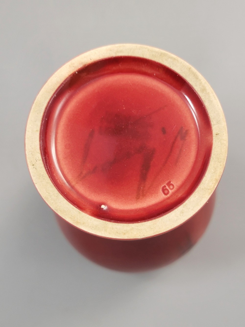 A red glazed earthenware vase featuring a baluster shape with an embossed roundel medallion near the rim. View V