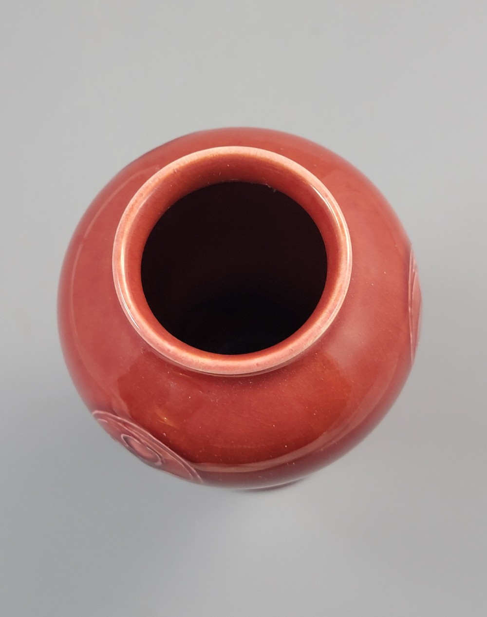 A red glazed earthenware vase featuring a baluster shape with an embossed roundel medallion near the rim. View VIII