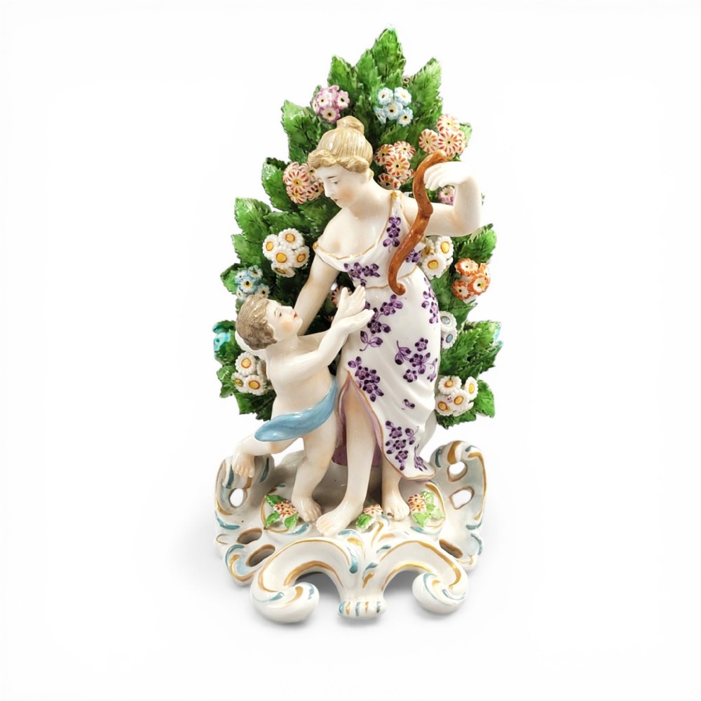A 19th-century Samson porcelain figurine depicting Venus and Cupid standing in front of a floral leaf bocage on a gilded scroll base.