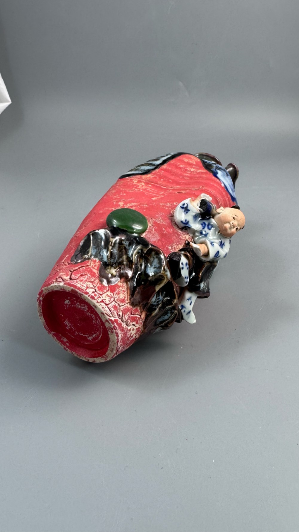 A Japanese Sumida Gawa baluster vase featuring a ribbed red surface, a dripping blue flambe glaze at the rim, and a sculpted karako figure on the side. View V