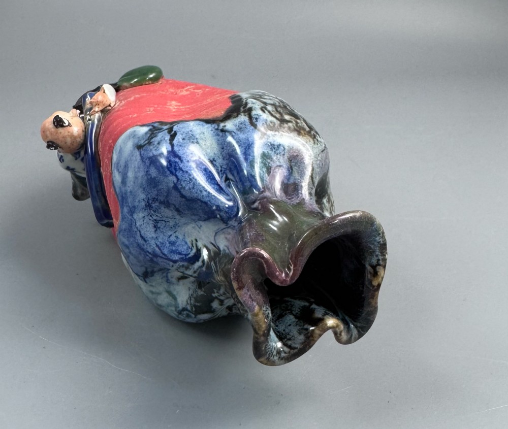 A Japanese Sumida Gawa baluster vase featuring a ribbed red surface, a dripping blue flambe glaze at the rim, and a sculpted karako figure on the side. View VI