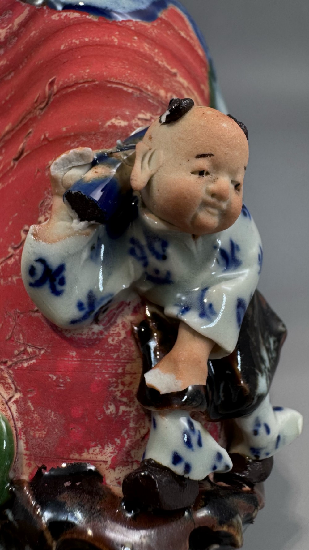 A Japanese Sumida Gawa baluster vase featuring a ribbed red surface, a dripping blue flambe glaze at the rim, and a sculpted karako figure on the side. View XIII