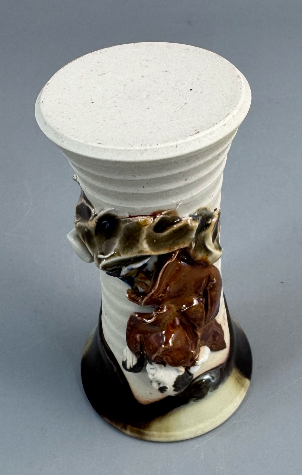 A Japanese Sumida Gawa stoneware vase featuring a ribbed cream body, dripping dark glaze along the flared rim, and an applied high-relief figure of a Rakan. View IX