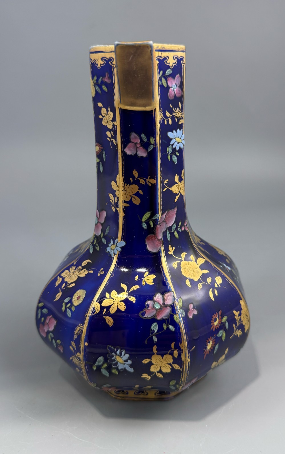 An octagonal cobalt blue ironstone ewer decorated with hand-painted Chinoiserie floral patterns and a gilded grotesque animal form handle. View II