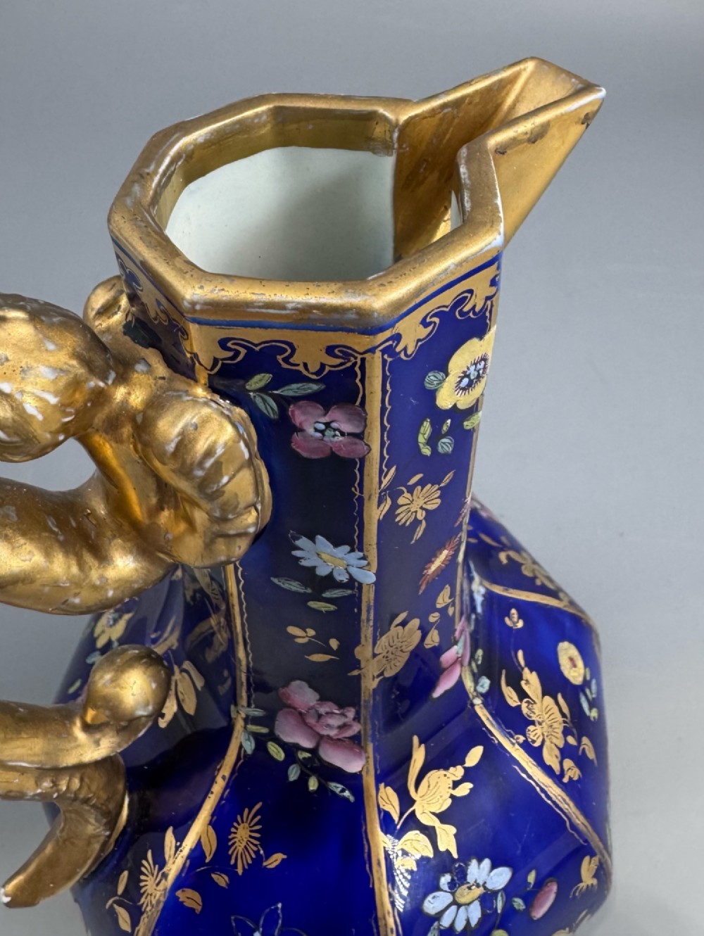 An octagonal cobalt blue ironstone ewer decorated with hand-painted Chinoiserie floral patterns and a gilded grotesque animal form handle. View VI