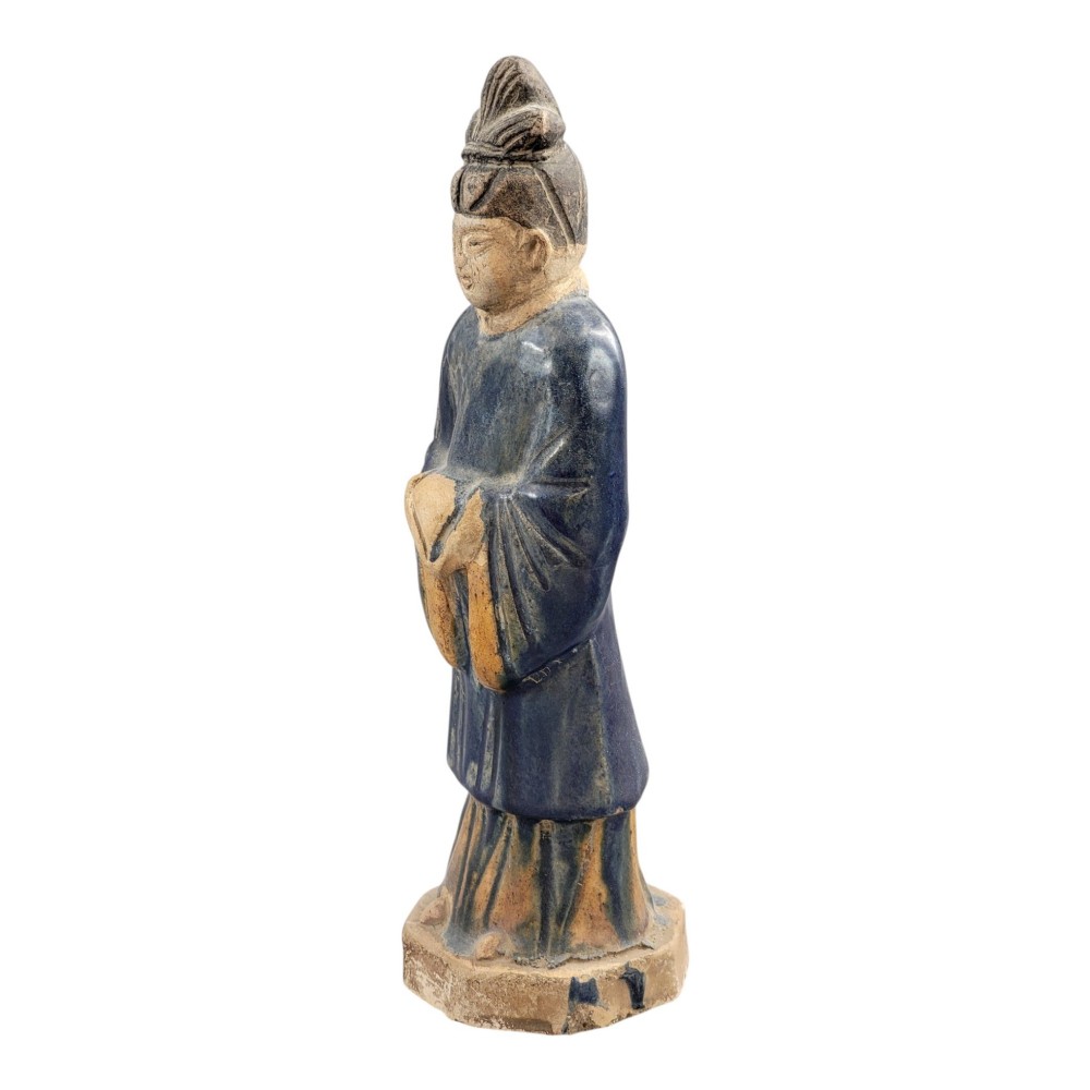 A Chinese Tang dynasty Sancai glazed earthenware figure of a court attendant standing on a hexagonal base with hands clasped under draped sleeves. View II