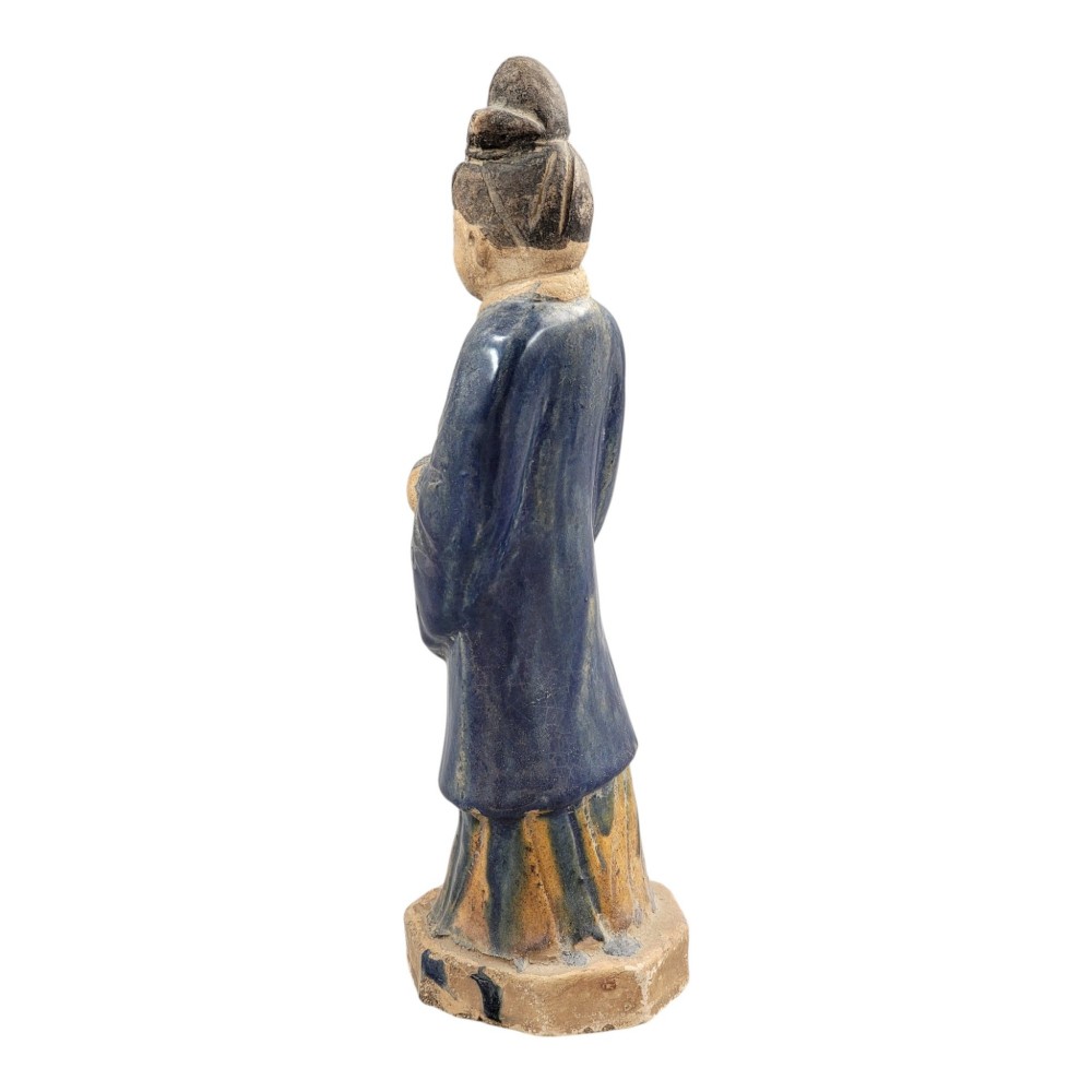 A Chinese Tang dynasty Sancai glazed earthenware figure of a court attendant standing on a hexagonal base with hands clasped under draped sleeves. View III