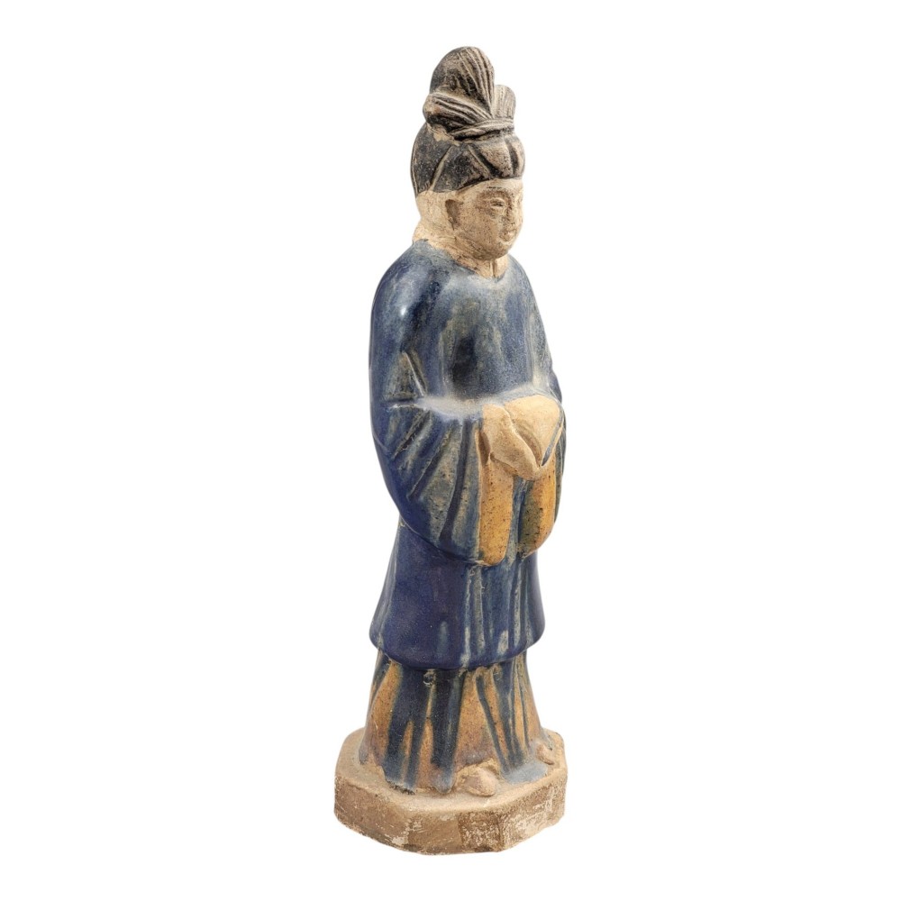 A Chinese Tang dynasty Sancai glazed earthenware figure of a court attendant standing on a hexagonal base with hands clasped under draped sleeves. View VI