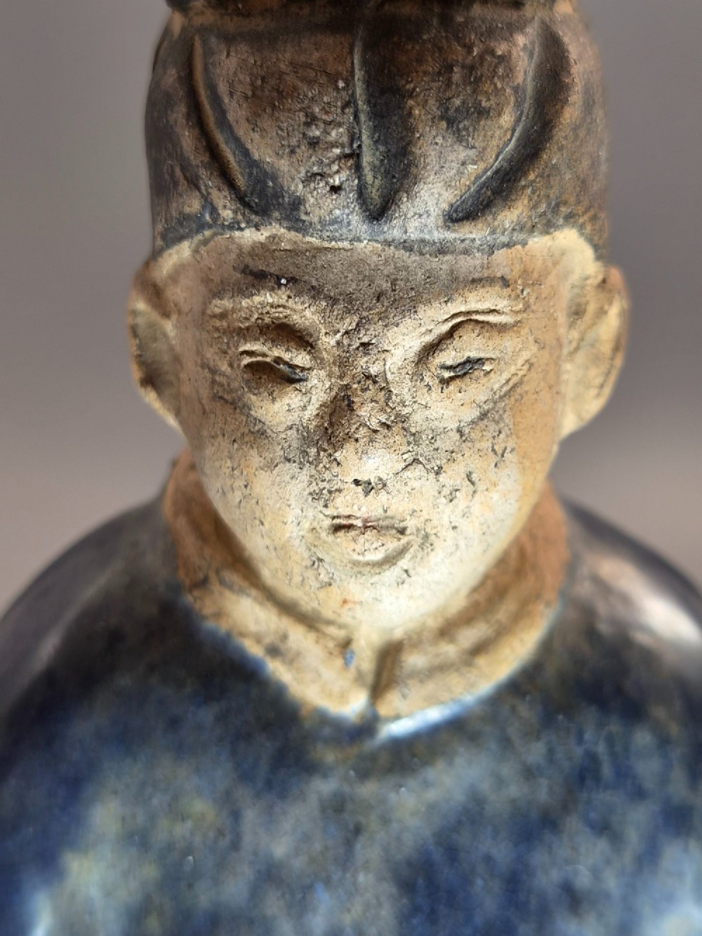 A Chinese Tang dynasty Sancai glazed earthenware figure of a court attendant standing on a hexagonal base with hands clasped under draped sleeves. View X