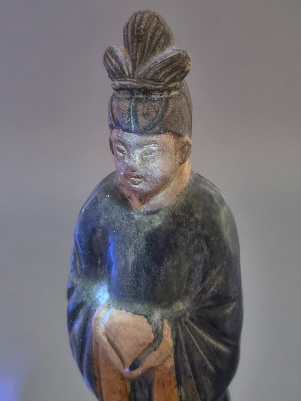 A Chinese Tang dynasty Sancai glazed earthenware figure of a court attendant standing on a hexagonal base with hands clasped under draped sleeves. View XII