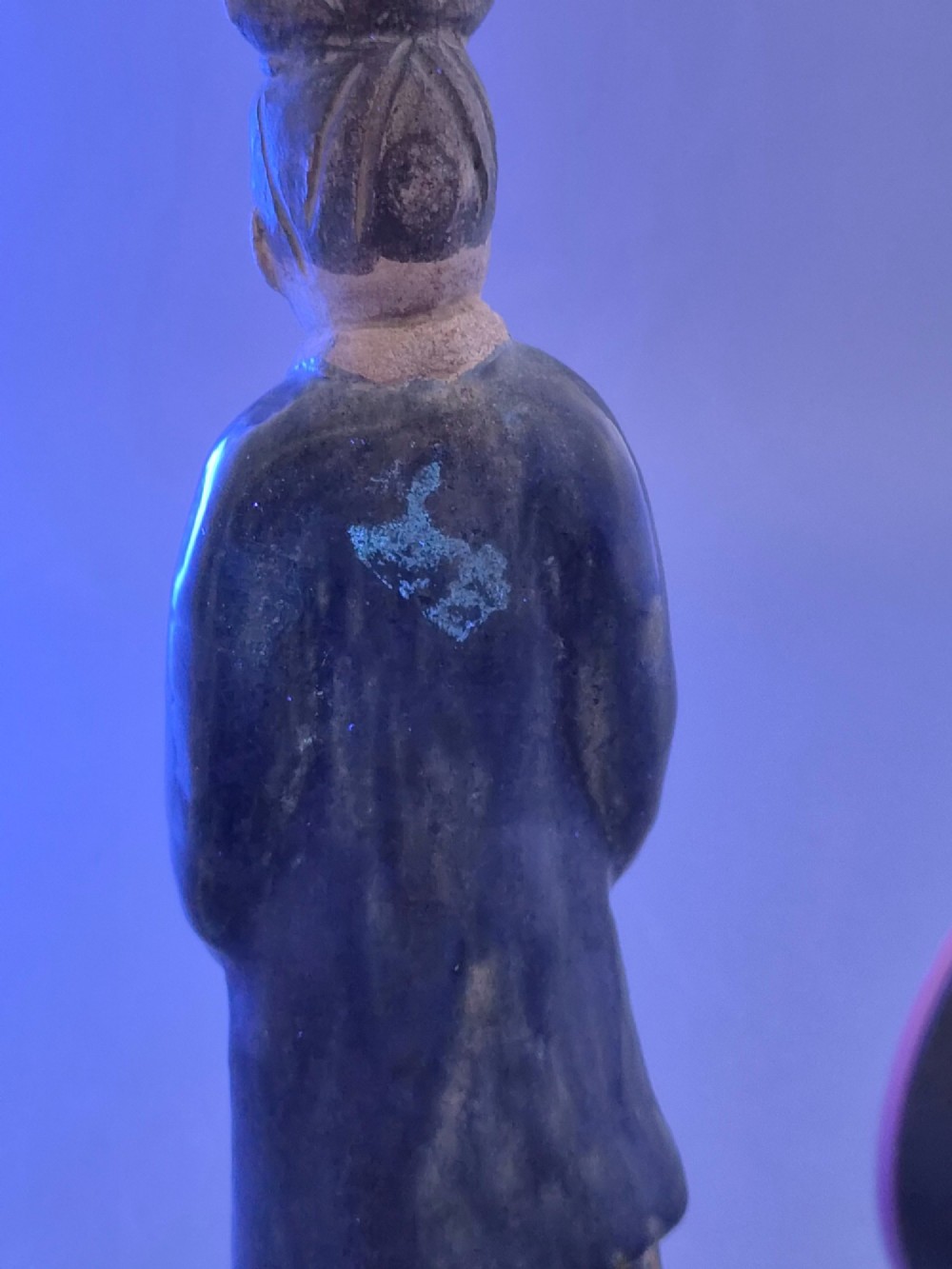 A Chinese Tang dynasty Sancai glazed earthenware figure of a court attendant standing on a hexagonal base with hands clasped under draped sleeves. View XV