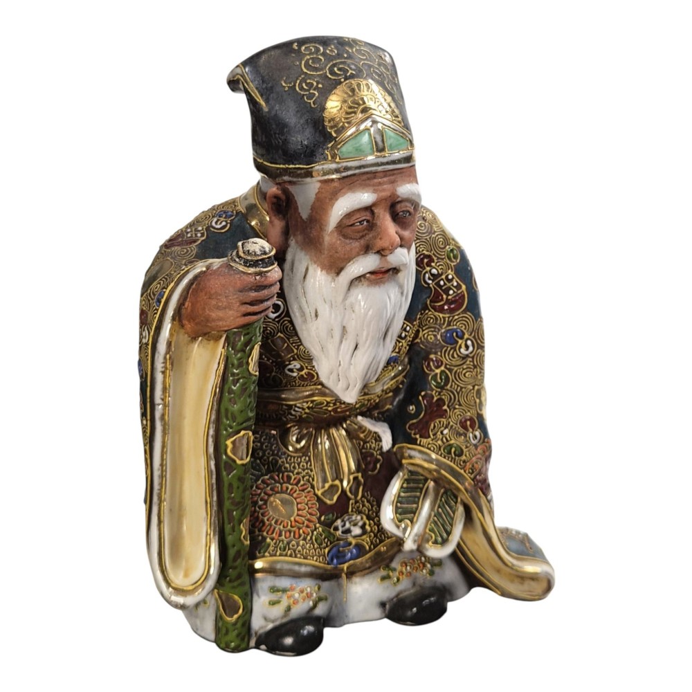 A Japanese Kutani porcelain figurine depicting Jurojin with a long white beard holding a staff, decorated in polychrome overglaze enamels and gold details.