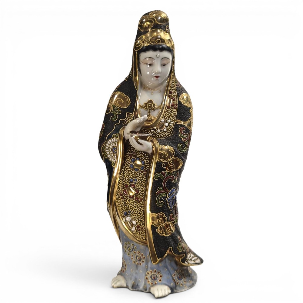 A standing Japanese Kutani porcelain figurine of Kannon with detailed black and gold enamelled robes and a white glazed face.