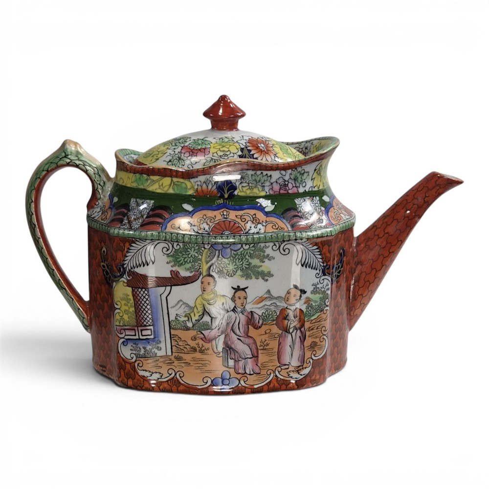 An antique Masons ironstone oval teapot featuring a red scale pattern and a hand-painted Chinoiserie scene with figures.
