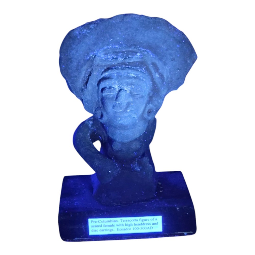 A Pre-Columbian earthenware terracotta sculpture depicting a seated female figure with a flared headdress, mounted on a rectangular dark wooden base. View XIII