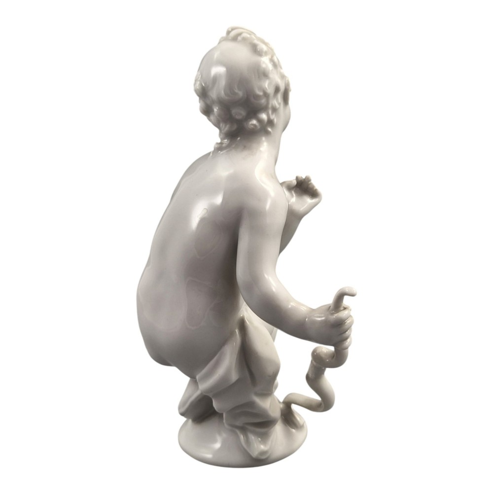 A glazed white porcelain figurine depicting a crouching winged cherub holding a curved bow on a circular base. View V