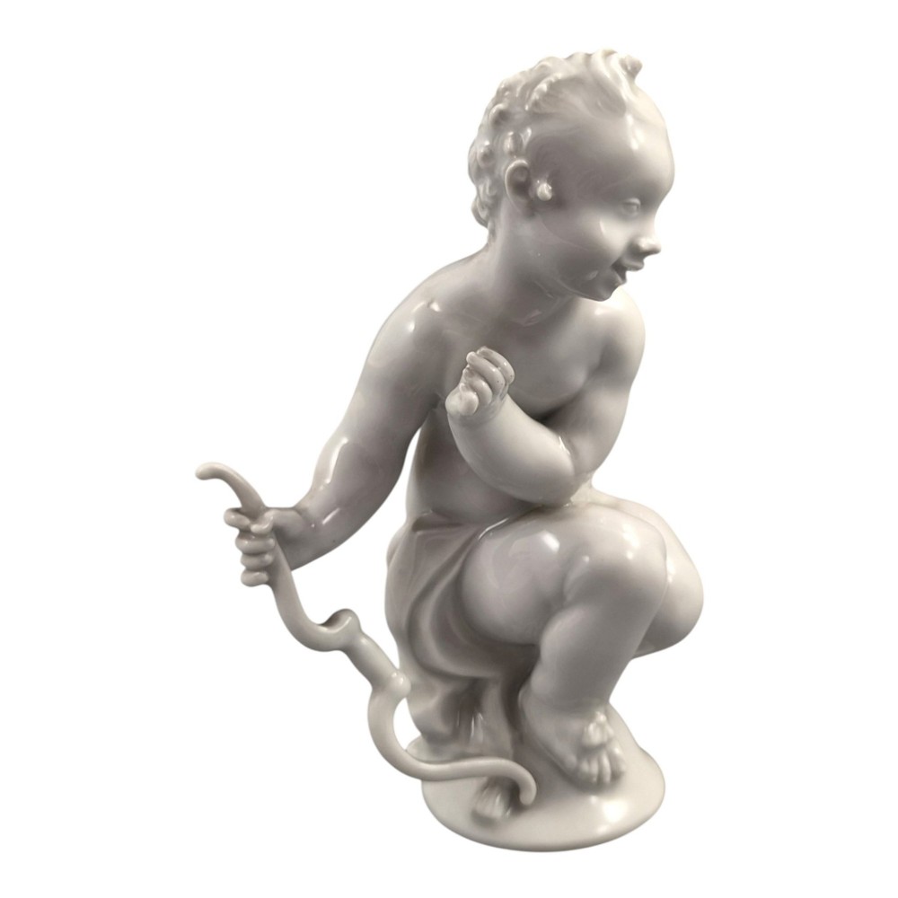 A glazed white porcelain figurine depicting a crouching winged cherub holding a curved bow on a circular base. View VII
