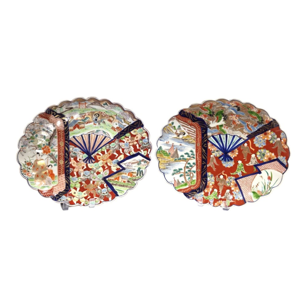 A pair of round antique Japanese Arita Imari porcelain charger plates featuring scalloped edges, fan motifs, landscape scenes, and iron red, cobalt blue, and green enamels.