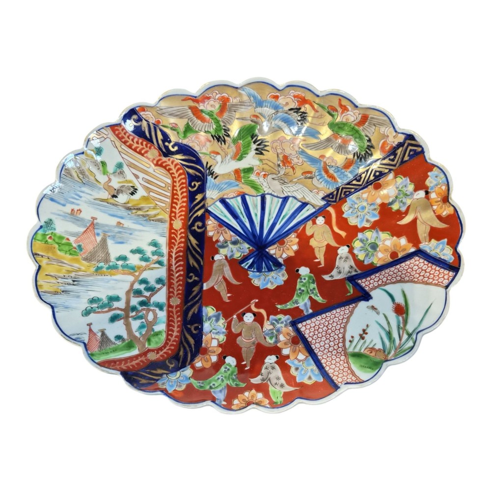A pair of round antique Japanese Arita Imari porcelain charger plates featuring scalloped edges, fan motifs, landscape scenes, and iron red, cobalt blue, and green enamels. View VI