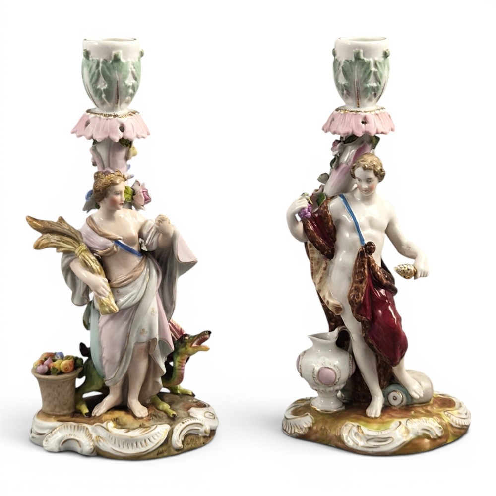 A pair of late nineteenth-century Volkstedt polychrome porcelain allegorical candlesticks depicting classical figures representing Summer and Autumn on rococo scroll bases.