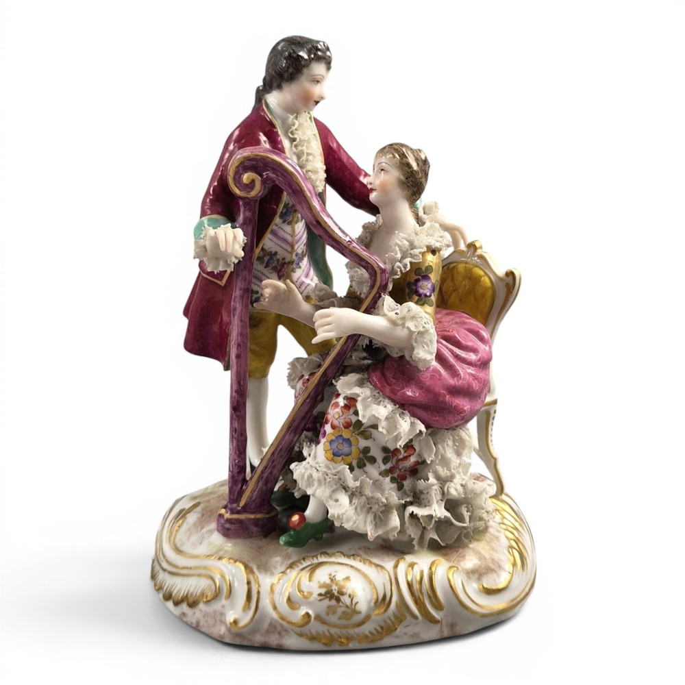 A 19th-century Paris porcelain figural group depicting a man standing behind a seated woman playing a harp, featuring porcelain lace trim and gold scrollwork.